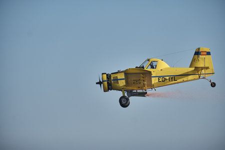A vintage single-engine aircraft with a propeller flying in a perfectly clear blue sky