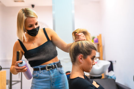 A shot of a female hairdresser in a medical mask doing her job - new normalの写真素材
