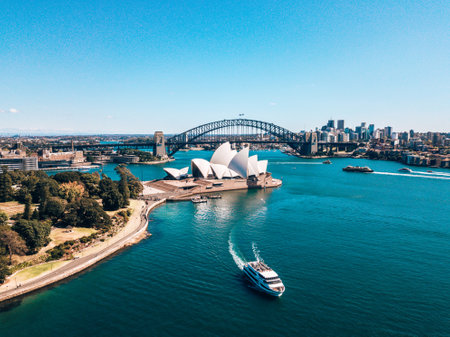 An aerial shot of Sydney center by the park near Sydney Opera house, harbor bridge, and city downtown with boats going past the opera houseのeditorial素材