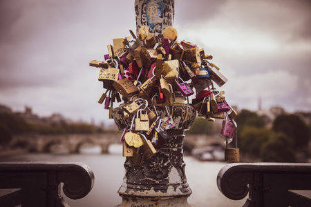 A selective focus closeup shot of numerous padlocks attached to the metal column of the bridge to "lock their love", river Seine, Paris, Franceのeditorial素材