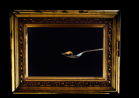 A vintage golden photo frame with single blue mussel on a fork against a black backgroundの写真素材