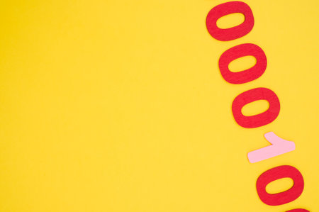 A top view of red and pink binary codes on a bright yellow surface