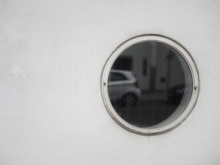 A closeup shot of a circular  window on a white wall