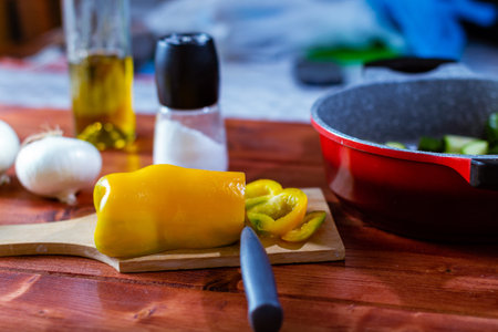 A closeup of a yellow bell pepper on a wooden cutting board in the kitchenの写真素材