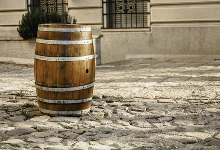 A wooden barrel on the pavement in front of a builiの写真素材