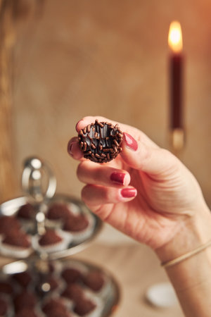 A selective focus shot of a female hand holding a bitten delicious Brazilian Brigadeiro, a traditional dessertの写真素材