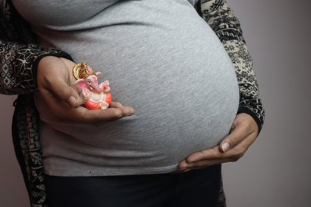 A closeup shot of a pregnant female holding a Ganesha figurineの写真素材