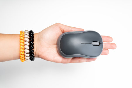 A closeup shot of a hand with bracelets holding a wireless mouse on a white background