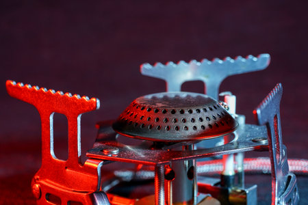 A selective focus shot of a portable gas burner in red lighting