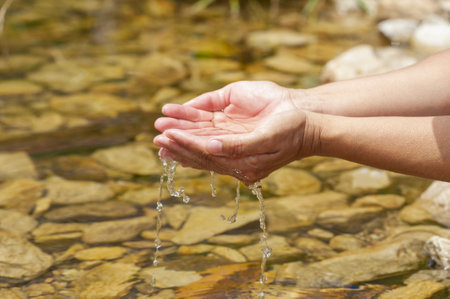 A closeup shot of human hands picking up water from a lakeの写真素材