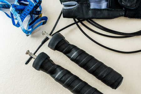 A closeup of a jump rope with a tape measure and muscle protector on the table
