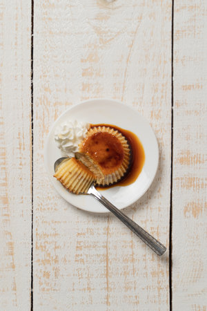 A vertical closeup of a plate of Creme Caramel dessert on the white plank tableの写真素材