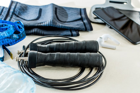 A closeup of a jump rope with a muscle protector and a tape measure on the table