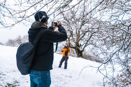 A man taking a photo of a woman at a snowy landscape during winter in the town of Opakua near Vitoria in Araba, Basque Country, Spainの写真素材