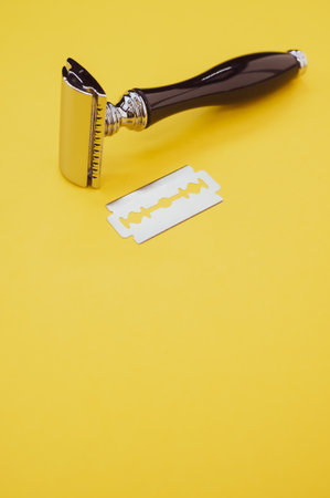 A vertical shot of a mechanical razor and blade isolated on yellow backgroundの写真素材