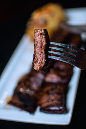 A selective focus shot of a piece of fresh tasty grilled steak on a forkの写真素材