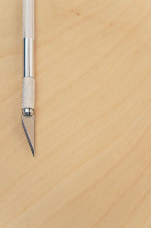 A vertical shot of the metallic scalpel on a plywood surfaceの写真素材