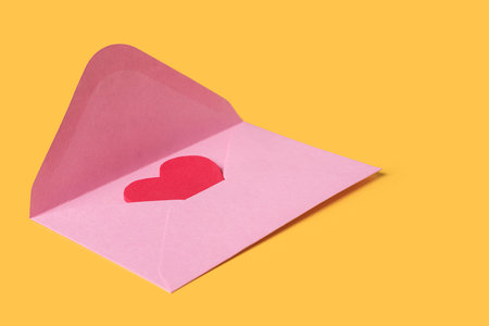 Minimal composition with a pink envelope with red heart inside for valentine day on yellow background. Copy space for textの写真素材