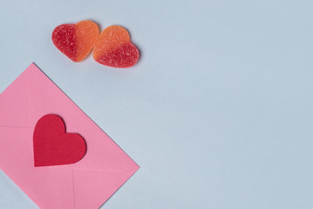 Minimal composition with a pink envelope with red heart inside, and a two sweet gummy hearts for valentine day. Copy space for texの写真素材