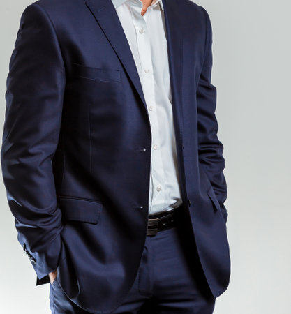 A shallow focus of an adult male wearing a white shirt with a dark blue suit and standing with his...