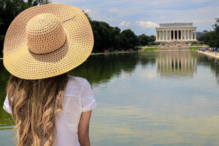 A girl with a hat from behind looking at the Lincoln memorialの写真素材