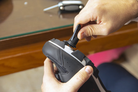 A closeup shot of a male assembling his cycling carbon road shoes and attaching cleats for pedals