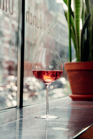 A beautiful shot of wine glass with wine near a windowの写真素材