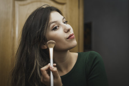 A young attractive female applying makeup in a mirrorの写真素材