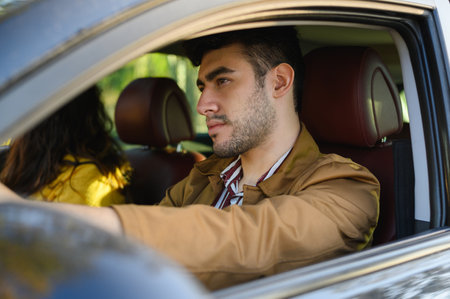 A young bearded Hispanic man driving a car with his girlfriend
