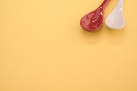 A high angle shot of small red and white spoons on a yellow backgroundの写真素材