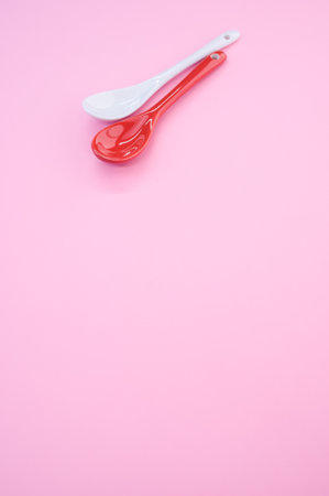A vertical overhead shot of red and white spoon shot on a studio on a pink backgroundの写真素材