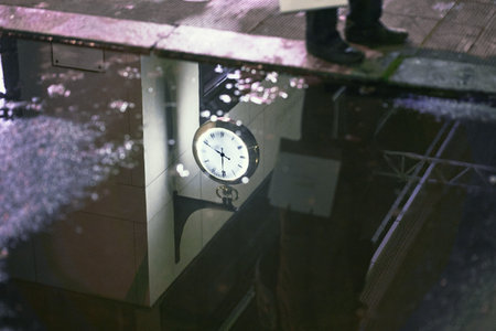A beautiful shot of the pool water with the reflection of a male standing and a clock