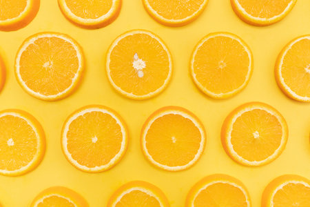 A top view of sliced oranges on a yellow backgrou