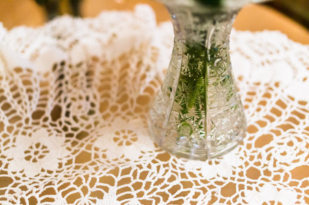 A closeup shot of a glass vase on a knitted piece of lace on the tableの写真素材