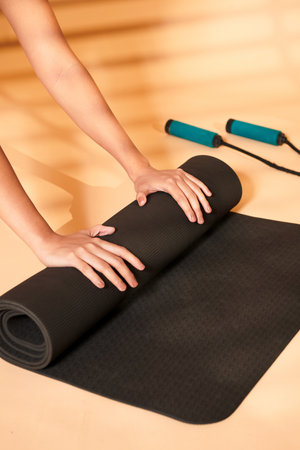 A closeup shot of a female rolling her fitness mat after a yogaの写真素材
