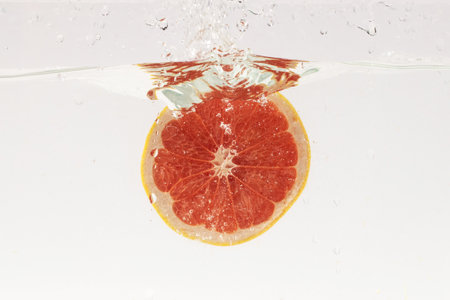 A slice of grapefruit bubbling in water on white backgroundの写真素材