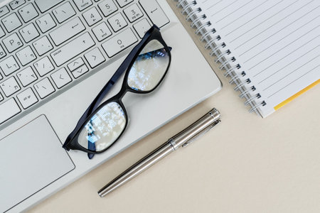 Top view of a desk with laptop, notebook, pen and glasses. Business or education concept. Copy space.の写真素材