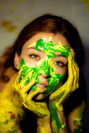 A beautiful girl with ginger hair looking at the camera while covered in yellow and grの写真素材