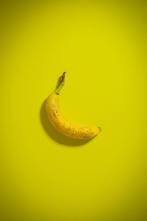 This photo represents a banana on a yellow background, this generates color consistency and is minimalの写真素材