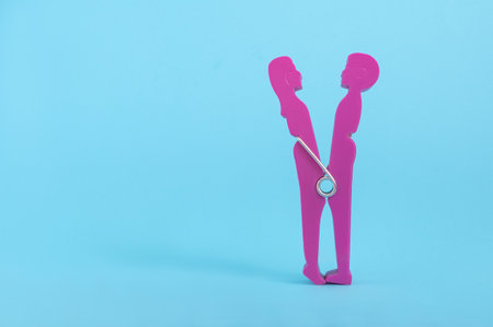 A closeup of a couple kissing each other clothespin isolated on a blue backgroundの写真素材