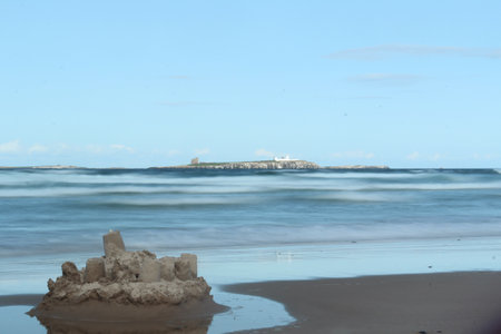 A fantastic shot of a sandy beach on a wavy sea and island background