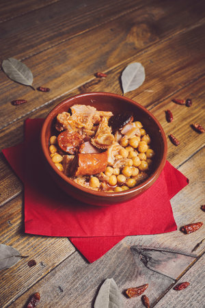 A typical Spanish food made with chickpeas, tripe and chorizo on a wooden tableの写真素材