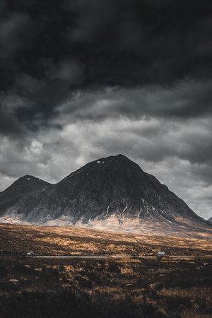 A vertical shot of a mesmerizing landscape with mountains under a stormy sky