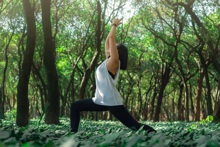 A young Caucasian female doing yoga and relaxing in a zen garden under the sunlightの写真素材