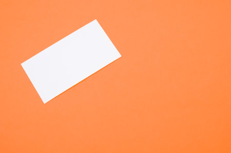 A closeup shot of white blank paper on an orange backgroundの写真素材