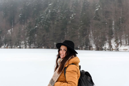 An attractive female smiling at the camera while standing on a snow-covered fieldの写真素材