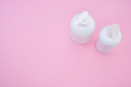 A high angle shot of white plastic bottles on a pink backgroundの写真素材