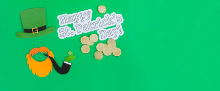 A Saint Patrick's Day banner with a green hat of a leprechaun, ginger beard, gold coins, and smoking pipeの写真素材