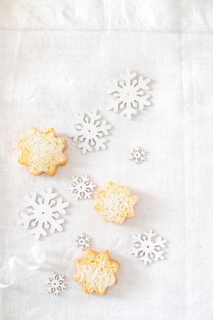 A vertical top view of wooden snowflakes in different sizes and delicious cookies with powdered sugarの写真素材