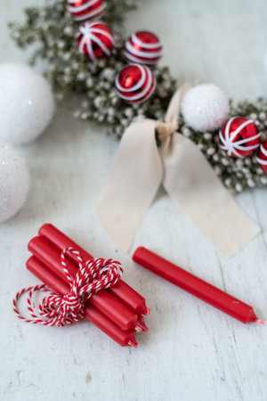 A selective focus shot of a Christmas wreath surrounded with Christmas balls and red candlesの写真素材